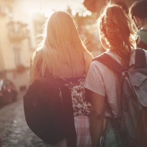 image of two girls traveling with backpacks. Homeschool Travel Learn at www.captivatingcompass.com