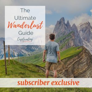 Image of man in blue shirt in the Swiss Alps admiring enormous mountains In the background with text overlay, The Ultimate Wanderlust Guide. Grab it here."
